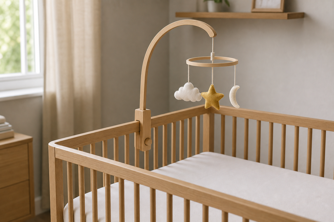 Light oak cot with a securely fitted wooden mobile hanger and cloud-and-star mobile hanging well above a clear newborn sleep space in a modern UK nursery